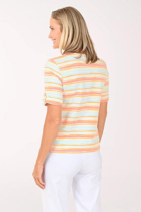 Woman wearing a colorful striped shirt and white pants on a white background