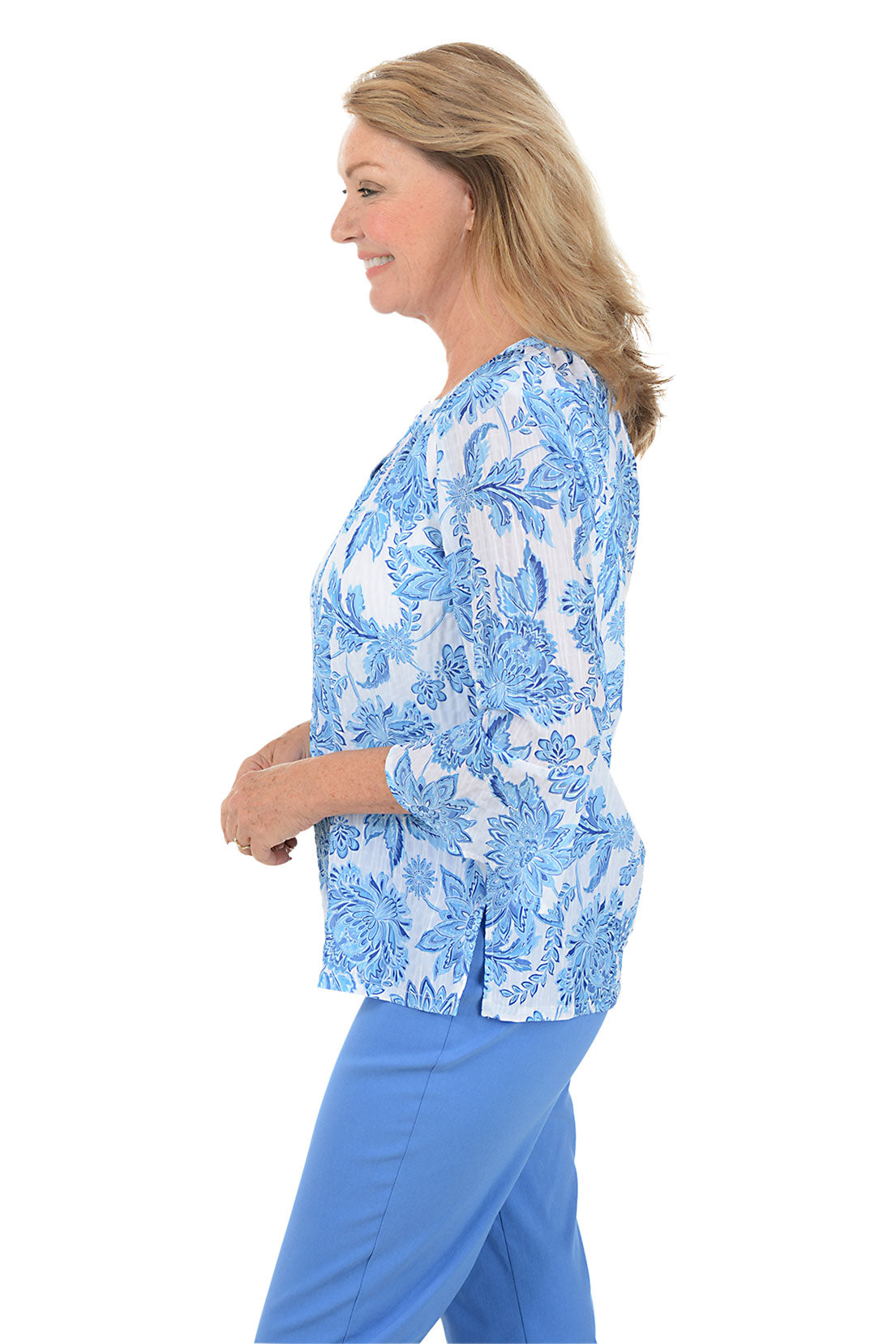 A woman wearing a 3/4 sleeve blue and white blouse with a floral pattern. Side shot.