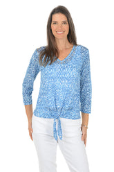 Woman wearing a blue patterned top with a white background.