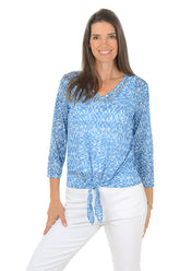 Woman wearing a blue patterned top with a white background. Second front shot.