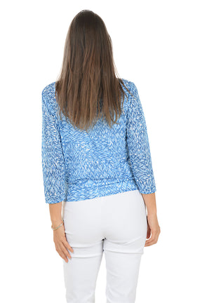 Woman wearing a blue patterned top with a white background. Back shot.