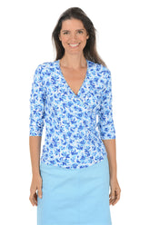 Woman wearing a blue floral blouse and light blue skirt on a white background.