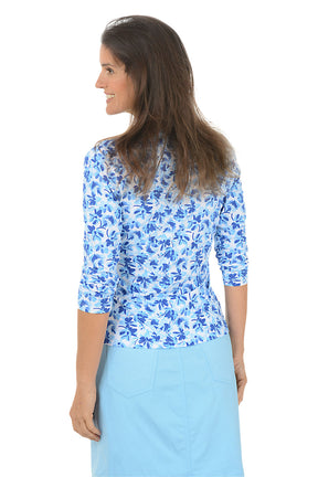 Woman wearing a blue floral blouse and light blue skirt on a white background. Back shot.