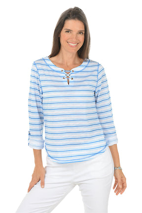 Woman wearing a blue and white striped shirt with a lace-up front, standing against a white background.