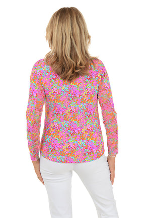 Woman wearing a colorful floral blouse with white pants on a white background. Back shot.