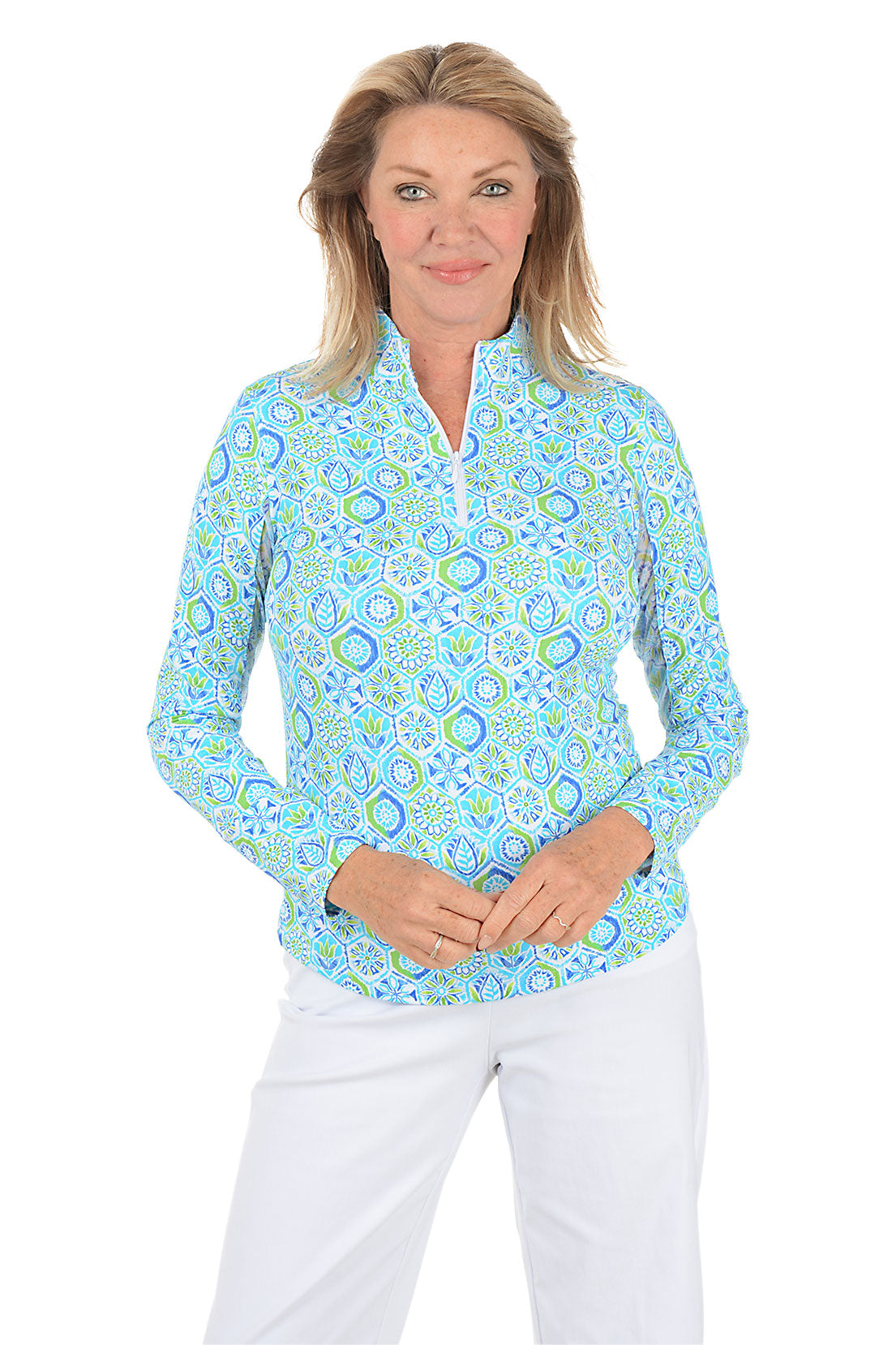 Woman wearing a patterned long-sleeve shirt and white pants on a white background.