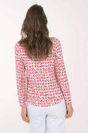 Woman wearing a red and white x and o patterned shirt on a white background