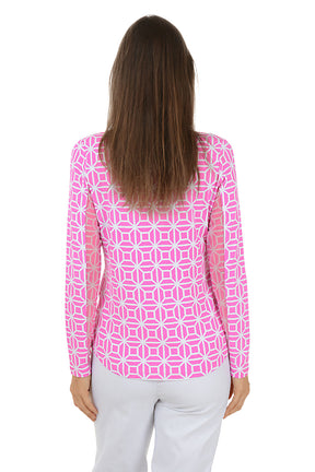 Woman wearing a pink geometric patterned shirt with white pants on a white background