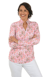Woman wearing a pink floral blouse with white pants on a white background