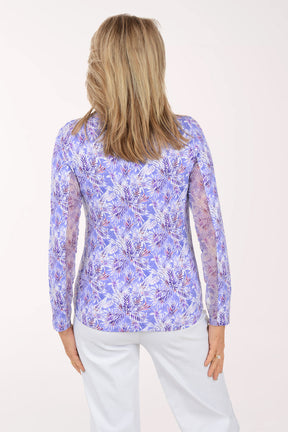 Woman wearing a purple floral patterned shirt against a white background