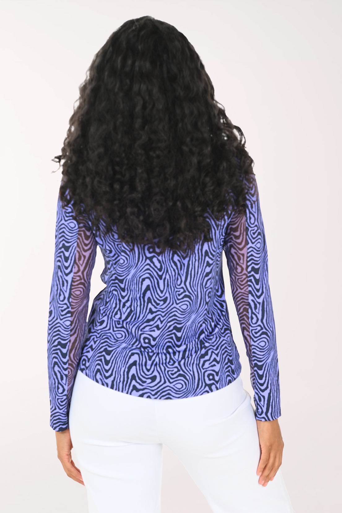 Woman wearing a blue patterned long-sleeve top on a white background