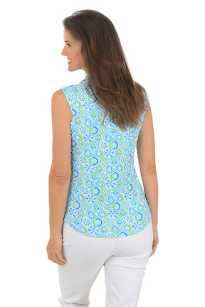 Woman wearing a sleeveless patterned top and white pants on a white background. Back shot.