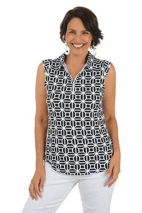 Woman wearing a sleeveless black and white patterned top with white pants on a white background