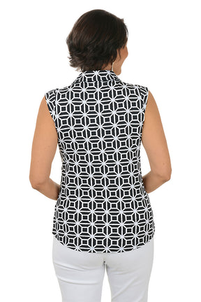 Woman wearing a sleeveless black and white patterned top with white pants on a white background