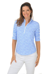 A woman wearing a royal blue and white striped sun shirt with a mandarin collar and white pants.
