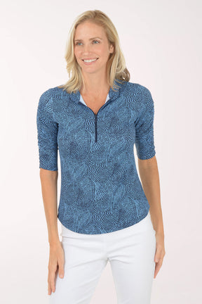 Woman wearing a blue patterned shirt with white pants on a white background