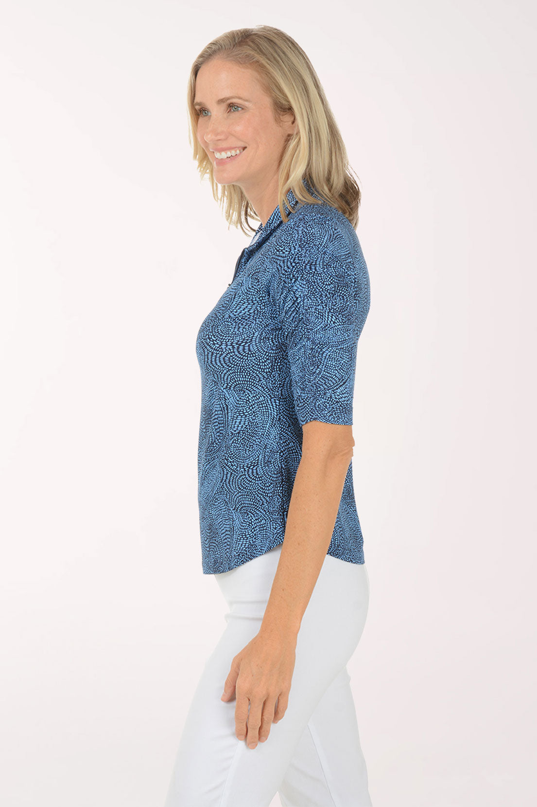 Woman wearing a blue patterned shirt with white pants on a white background