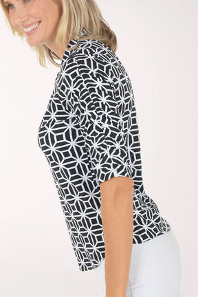 Woman wearing a black and white patterned shirt with a plain background