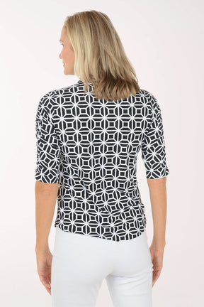 Woman wearing a black and white patterned shirt with a plain background