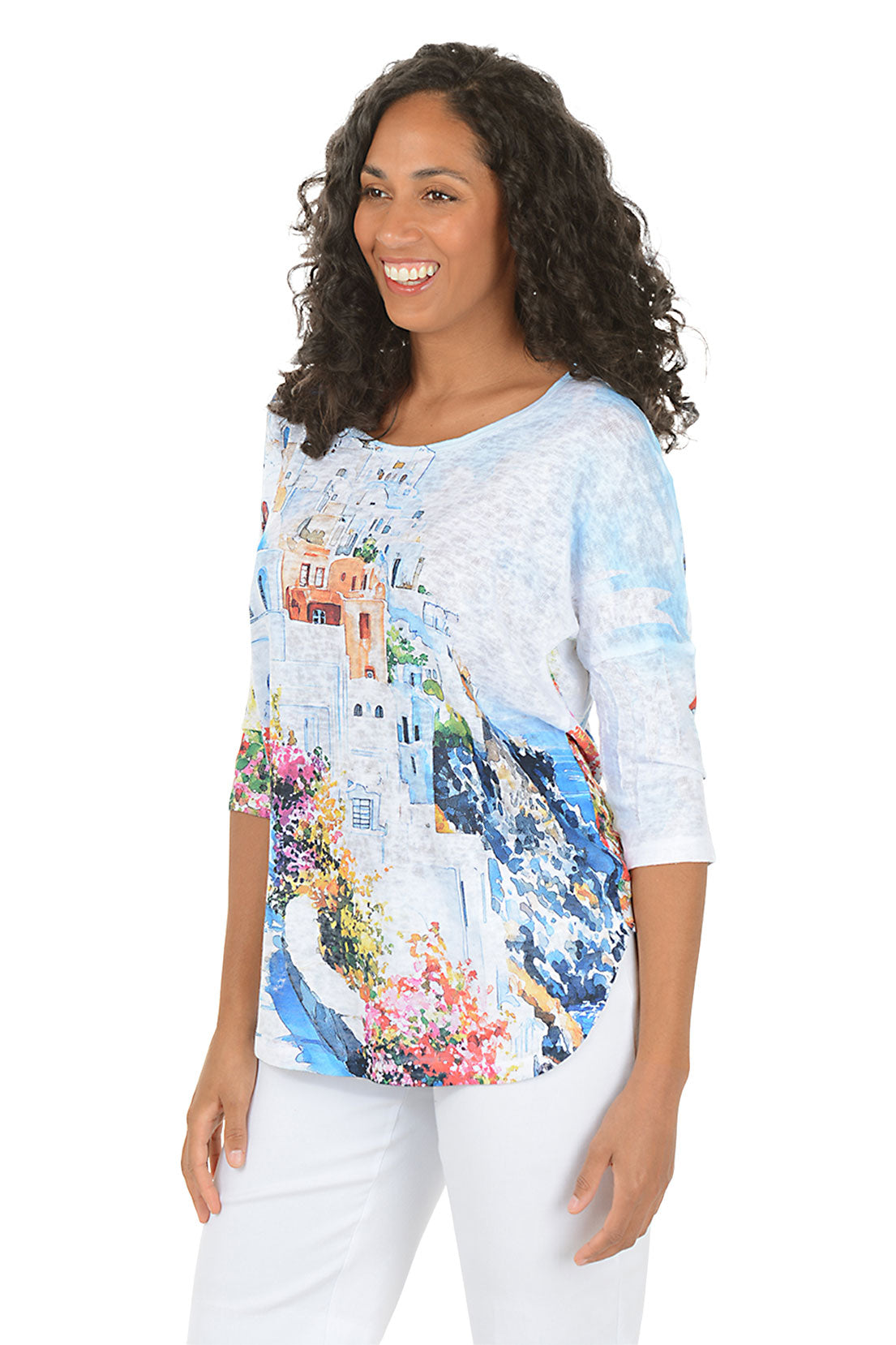 Woman wearing a colorful print top with a scenic design on a white background.