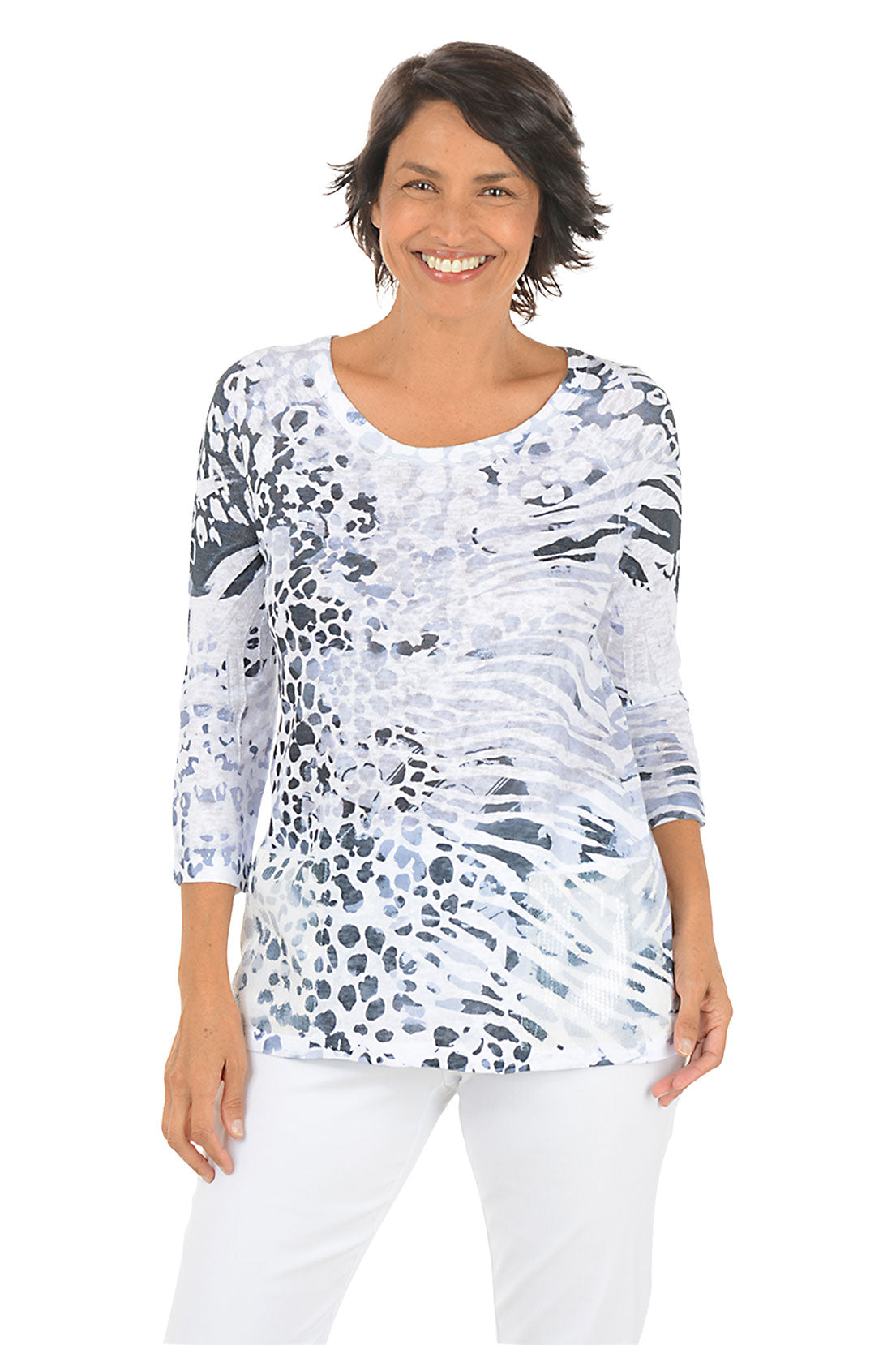 Woman wearing a patterned top and white pants on a white background