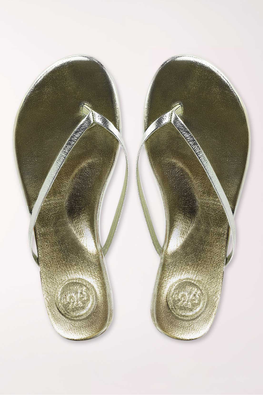 Pair of gold metallic sandals on a white background