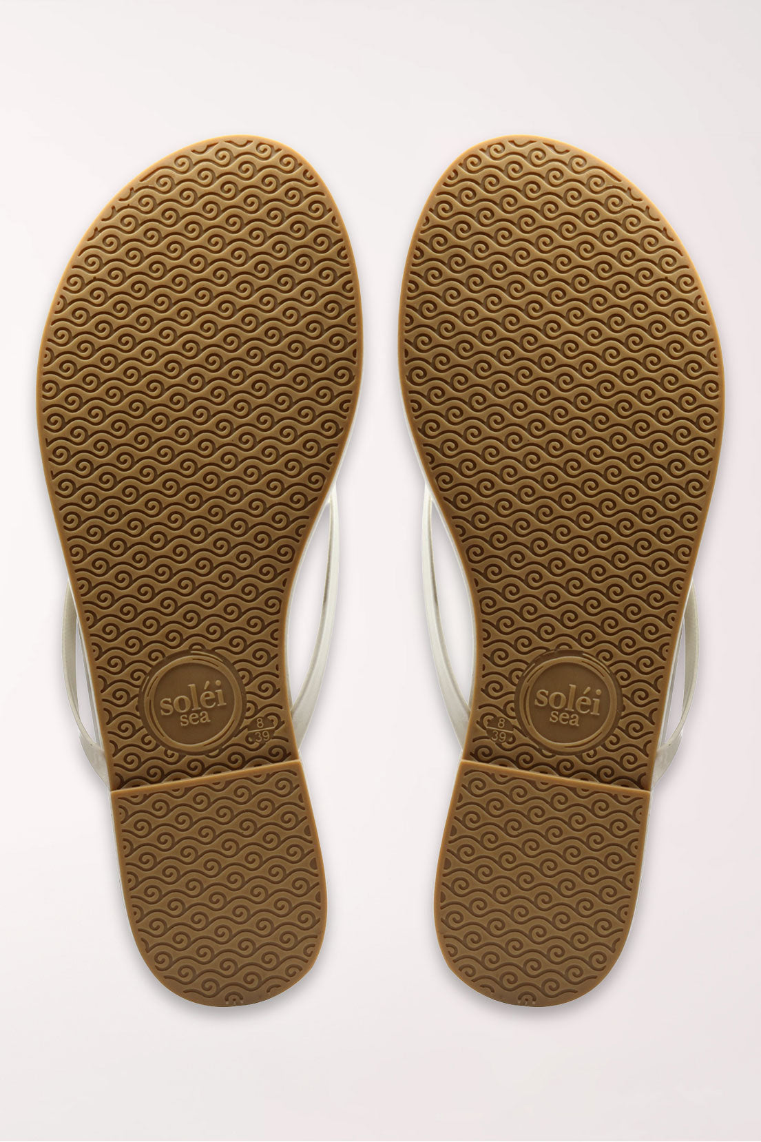 White flip-flop sandal with brown sole on a beige surface