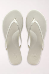 Pair of white flip-flops on a light gray background
