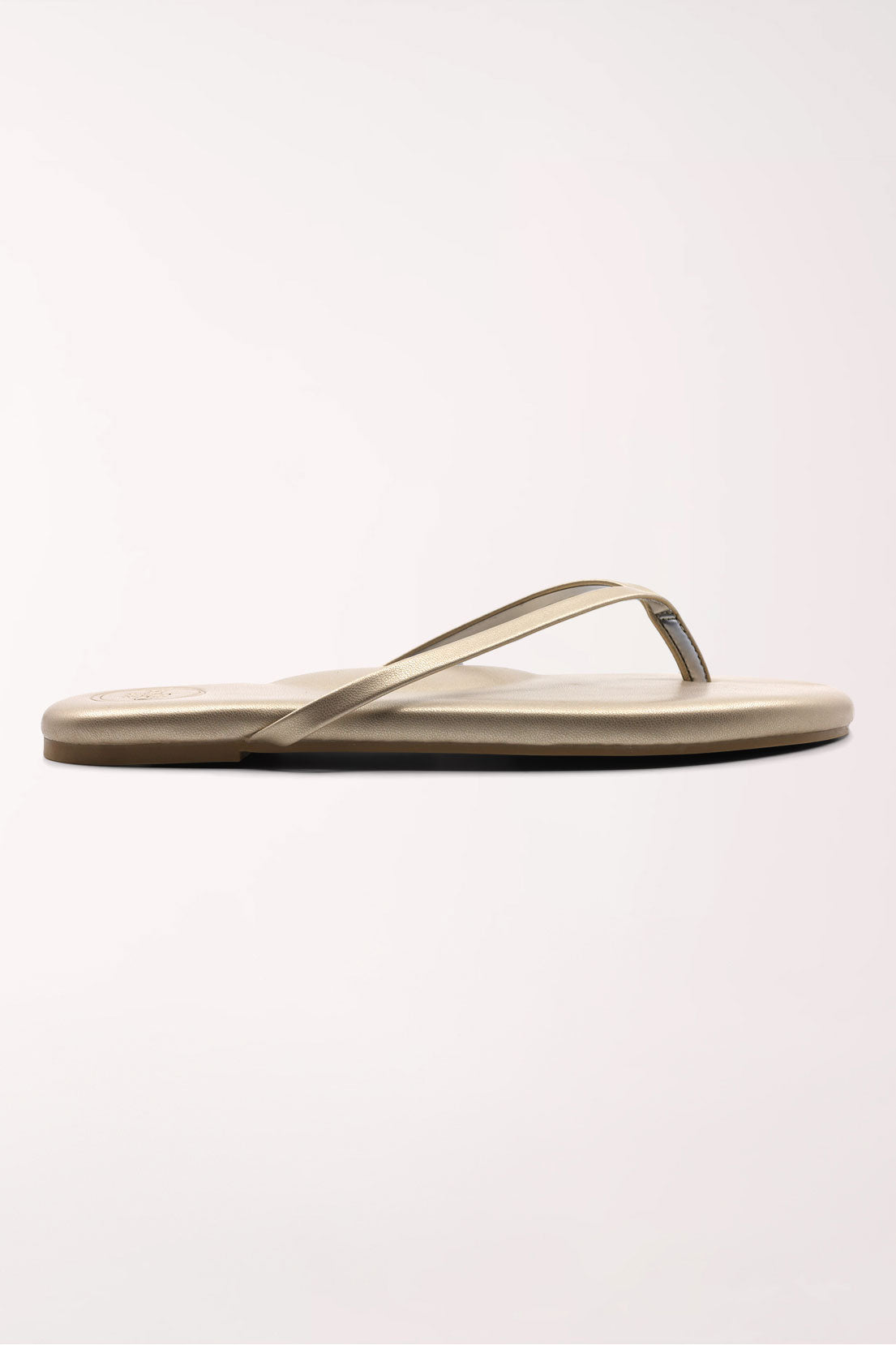 Pair of champagne gold flip-flops on a white background