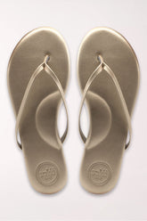 Pair of champagne gold flip-flops on a white background