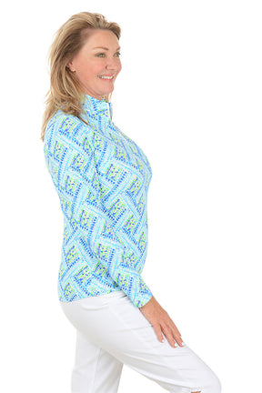 Woman wearing a blue patterned long-sleeve shirt on a white background. Side shot.