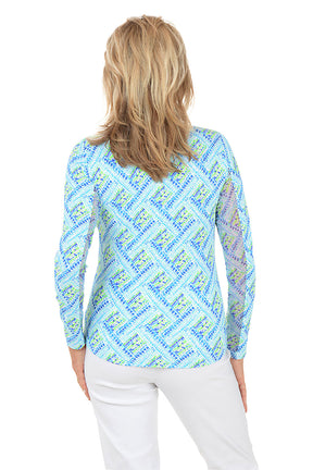 Woman wearing a blue patterned long-sleeve shirt on a white background. Back shot.