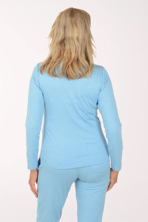 Woman wearing a light blue long-sleeve top and pants on a white background