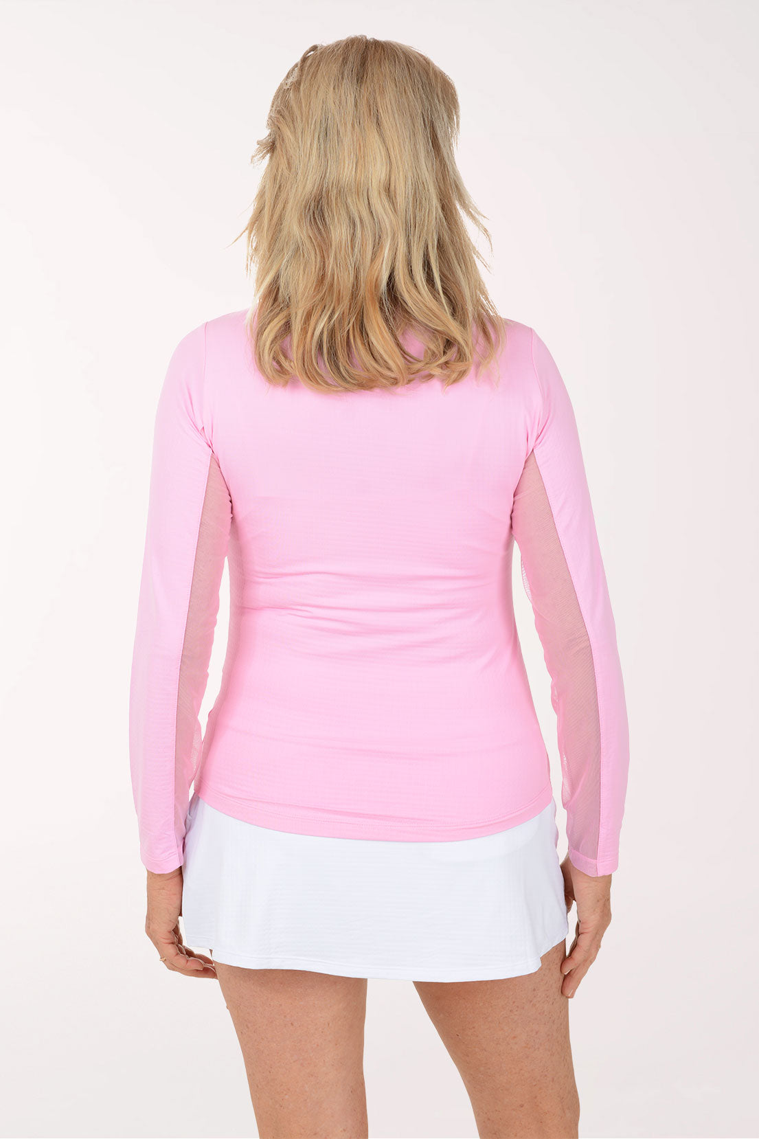 Woman wearing a pink long-sleeve top and white skirt on a white background