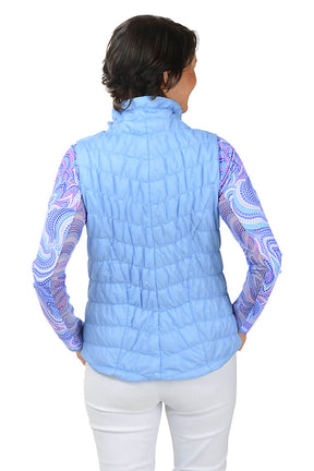 Woman wearing a light blue quilted vest with a colorful pattern on sleeves against a white background. Back shot.