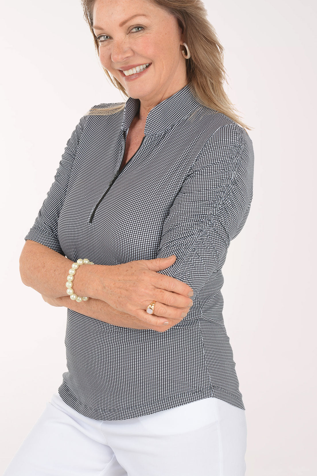 Woman wearing a black and white checkered short-sleeve shirt with a zipper on a white background. Detail shot.