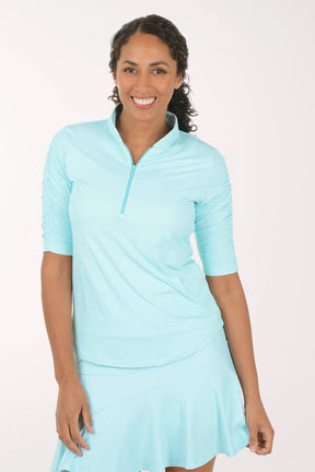 Woman wearing a seafoam green and white checkered short-sleeve shirt with a zipper on a white background. 