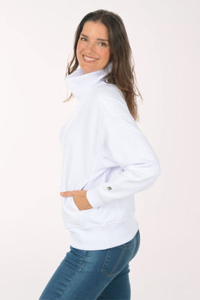 A woman wearing a white funnel neck sweater.