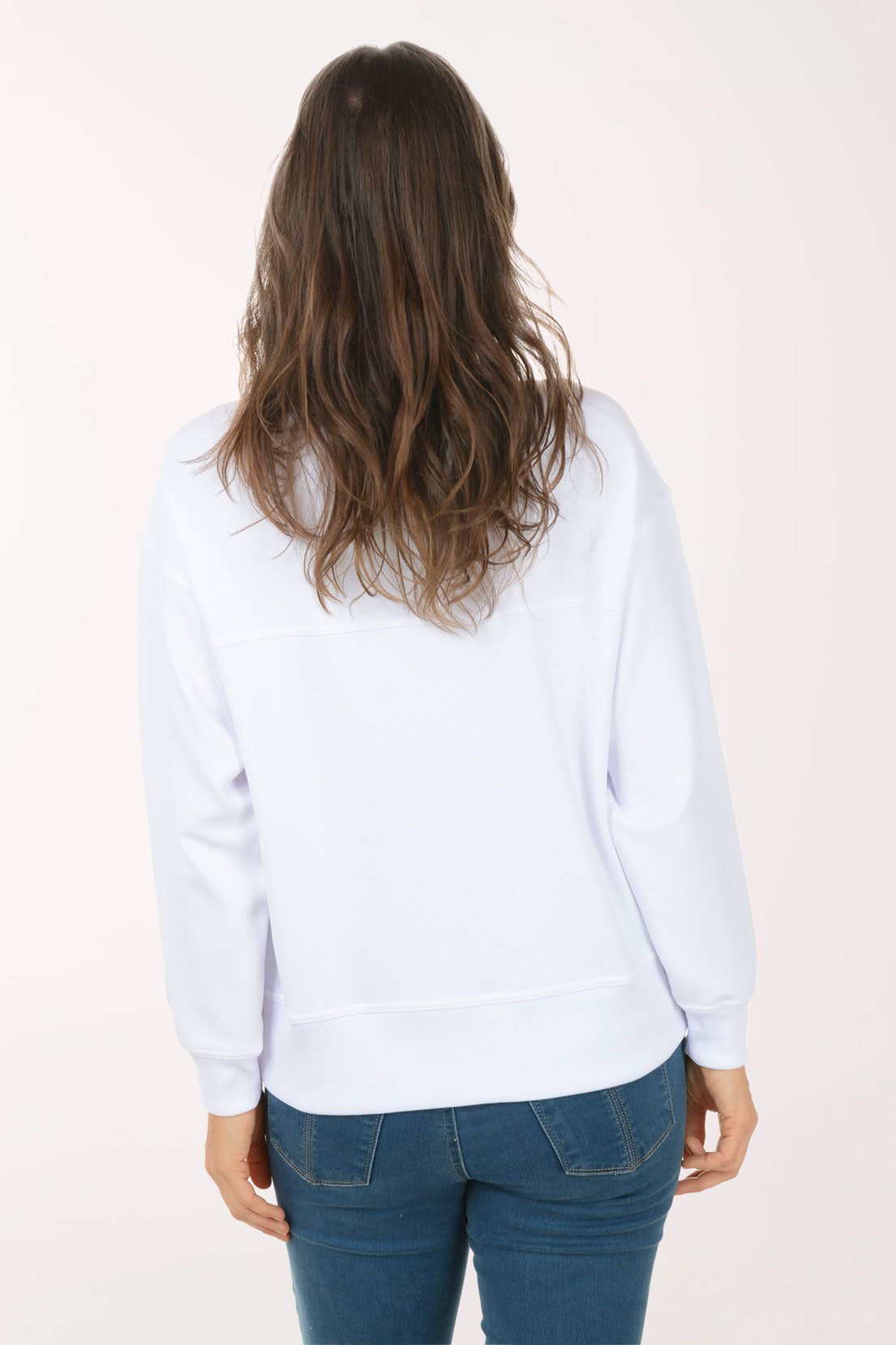 A woman wearing a white funnel neck sweater.