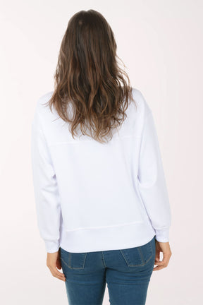 A woman wearing a white funnel neck sweater.