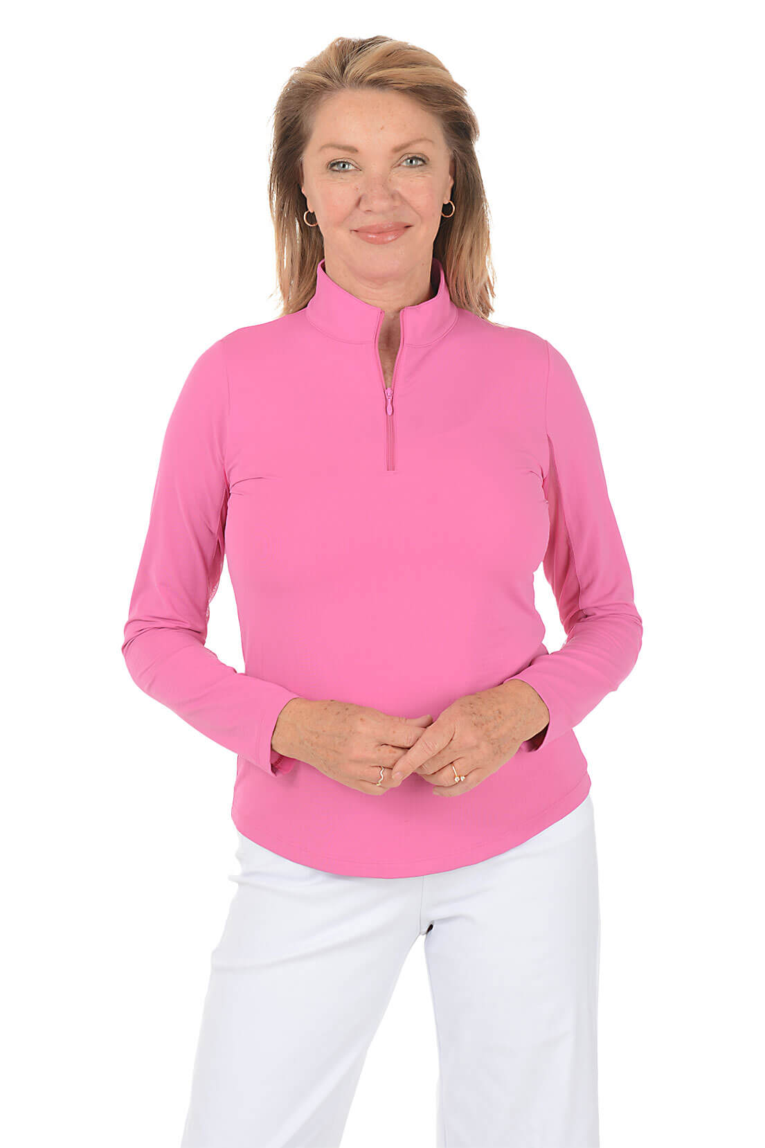 Woman wearing a rose pink long-sleeve top with a quarter zip and white pants on a white background