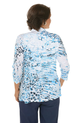 Woman wearing a blue floral cardigan over a white top on a white background. Back shot.