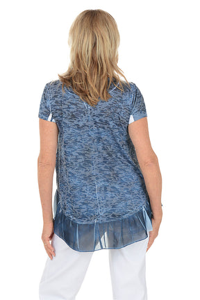 Woman wearing a blue patterned top with a white background. Back shot.