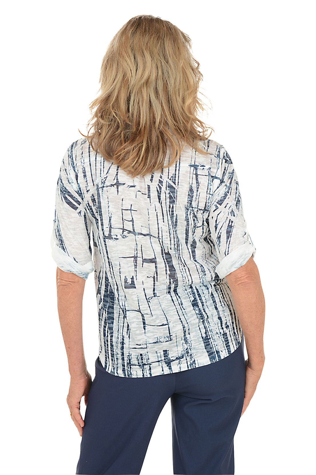 A woman wearing a white and navy 3/4 rolled sleeve top with a button detail and abstract pattern. Back shot.