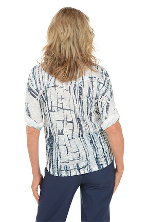 A woman wearing a 3/4 roll sleeve navy and white top. Back shot.