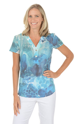 A woman wearing a blue v-neck short sleeve shirt with a button detail.