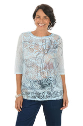 Woman wearing a light blue floral patterned top on a white background.