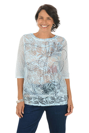 Woman wearing a light blue floral patterned top on a white background.