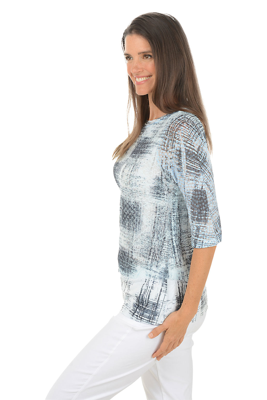 A woman wearing a 3/4 sleeve grey and white top with an abstract square pattern. Side shot.