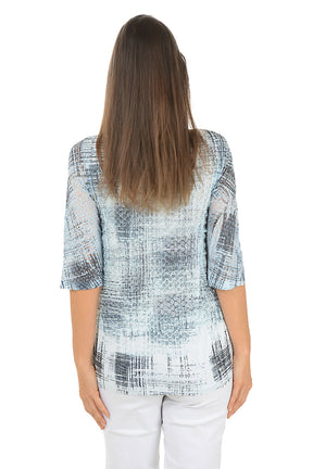 A woman wearing a 3/4 sleeve grey and white top with an abstract square pattern. Back shot.
